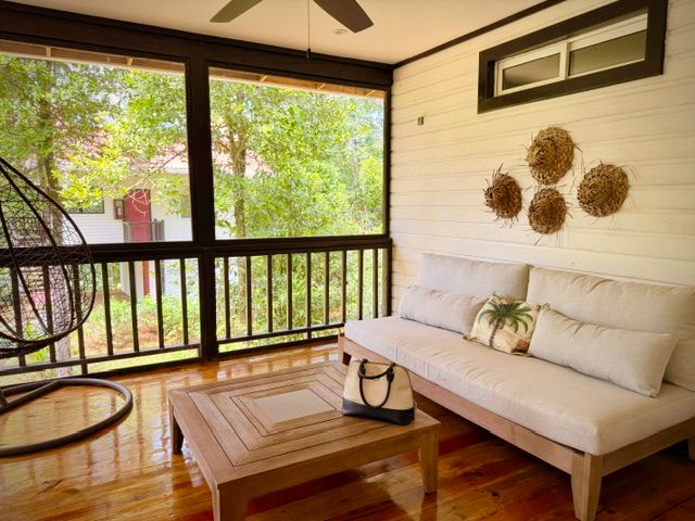 The screened outdoor living room: sofa, hanging egg chair and the jungle all around