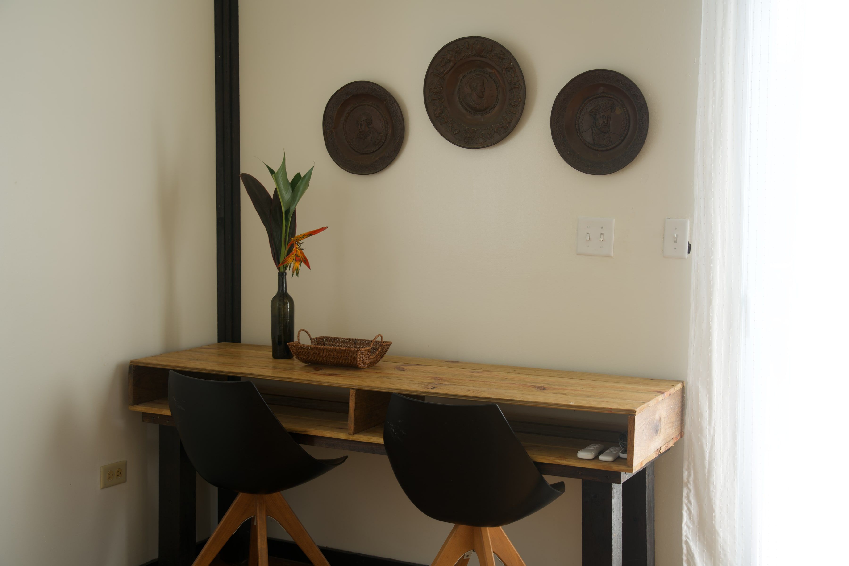 A wooden table for two, with three bronze plates on the wall