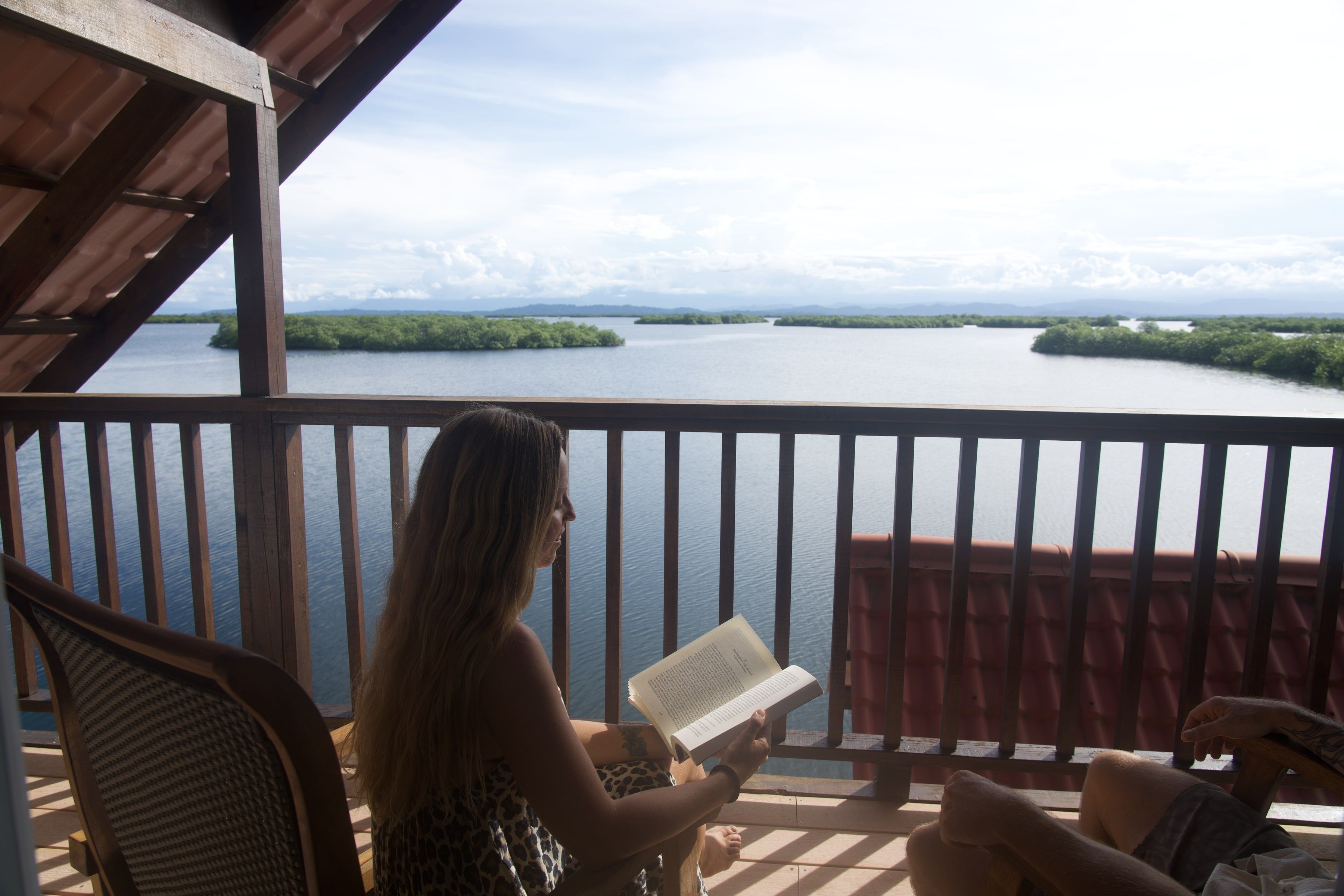 Someone reading in a rocking chair on the balcony, with the lagoon and the islands beyond