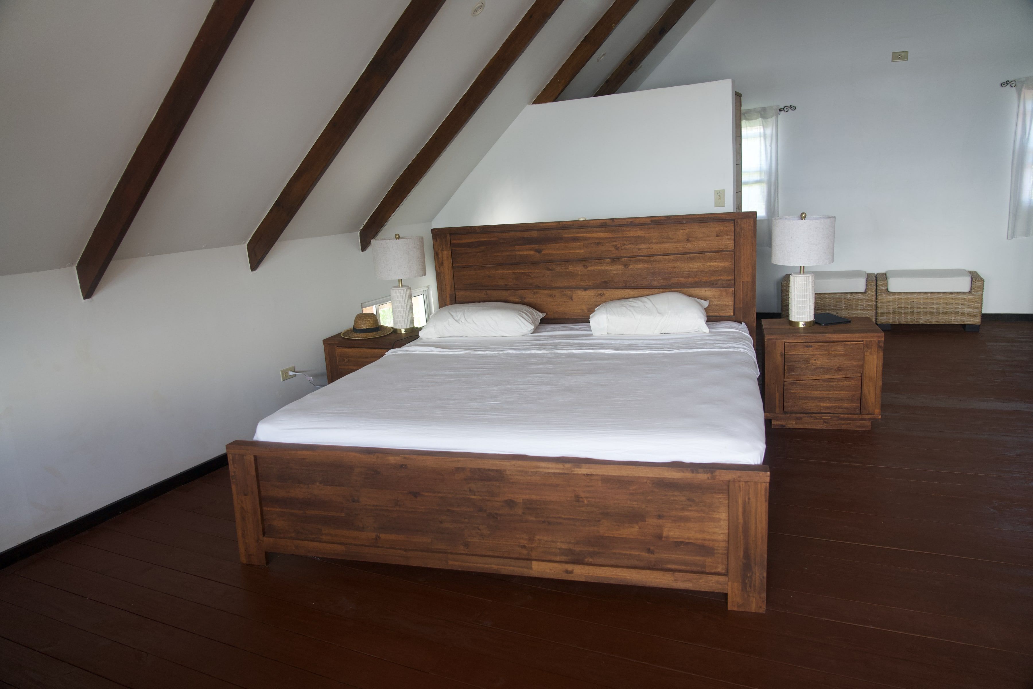 The king bed in the upstairs bedroom, under the roof beams