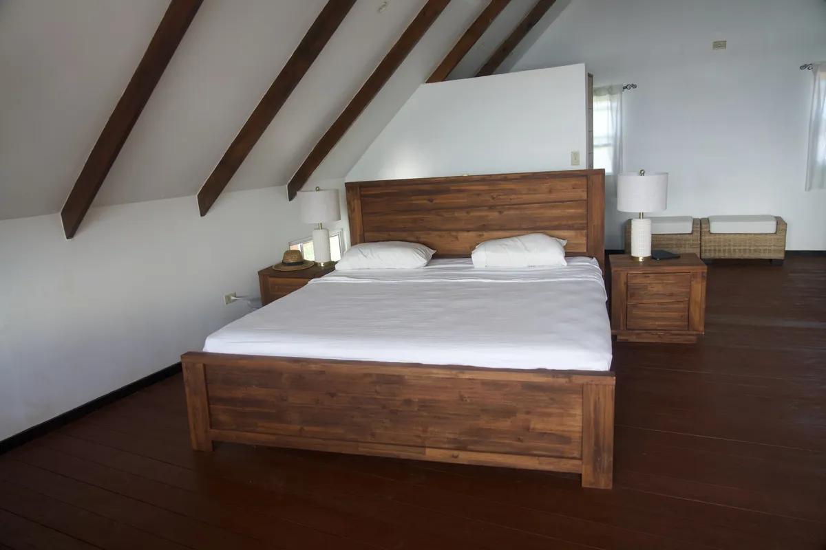 The king bed in the upstairs bedroom, under the roof beams