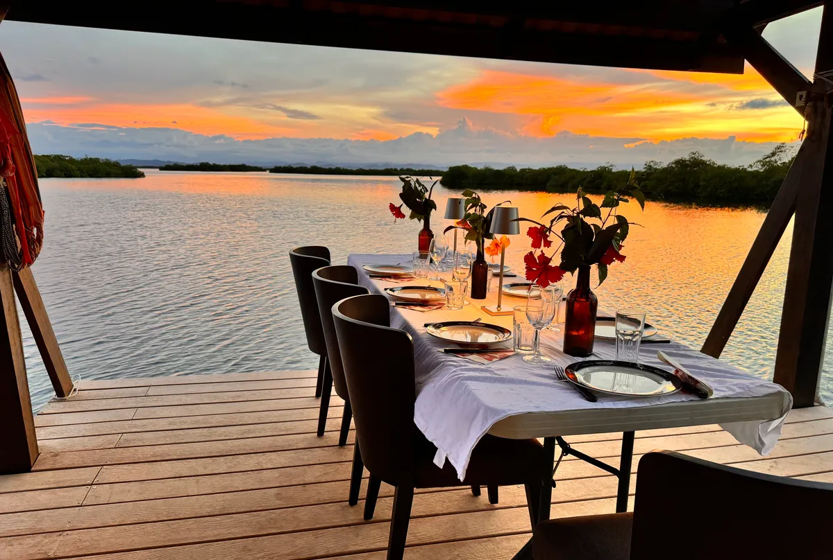 A table set on the terrace at sunset, over the lagoon