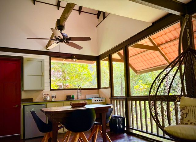 The screened outdoor living room: kitchenette, table and hanging egg chair