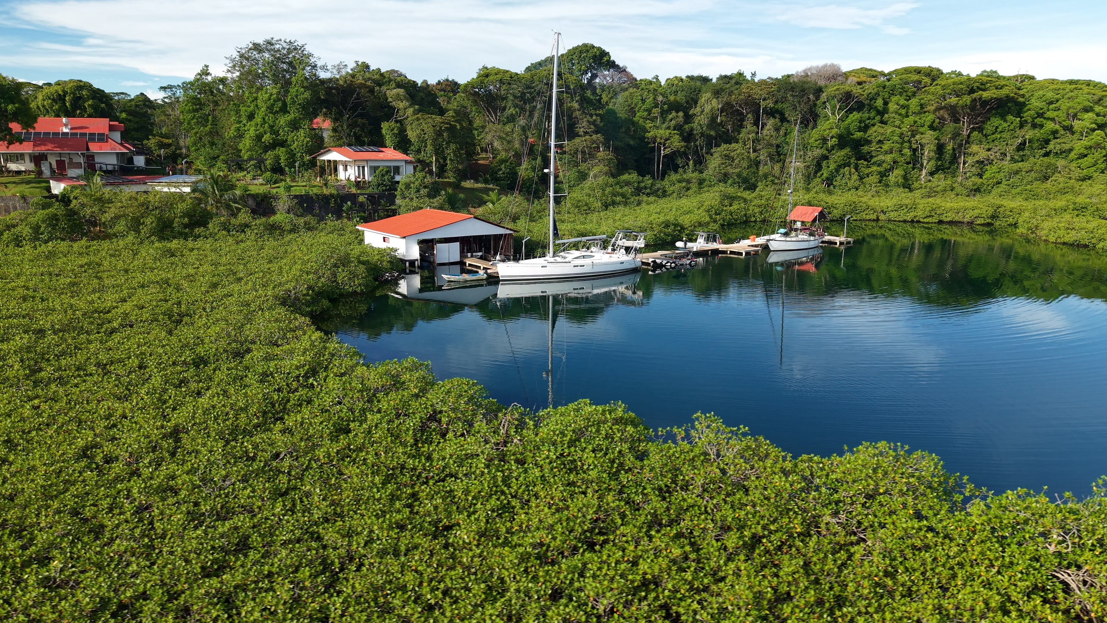 The resort's dock on the lagoon, with two sailboats tied up, among the mangroves