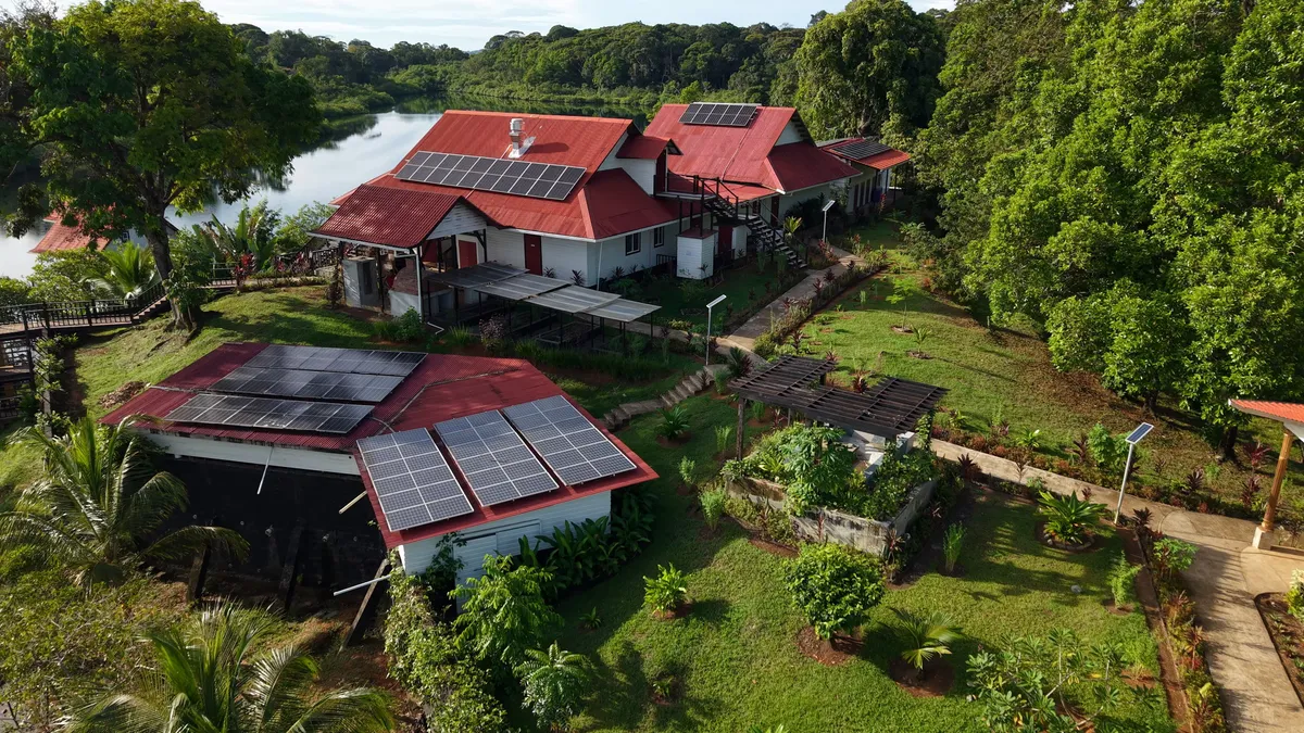 Solar panels on the resort's red roofs, beside the garden and the lagoon