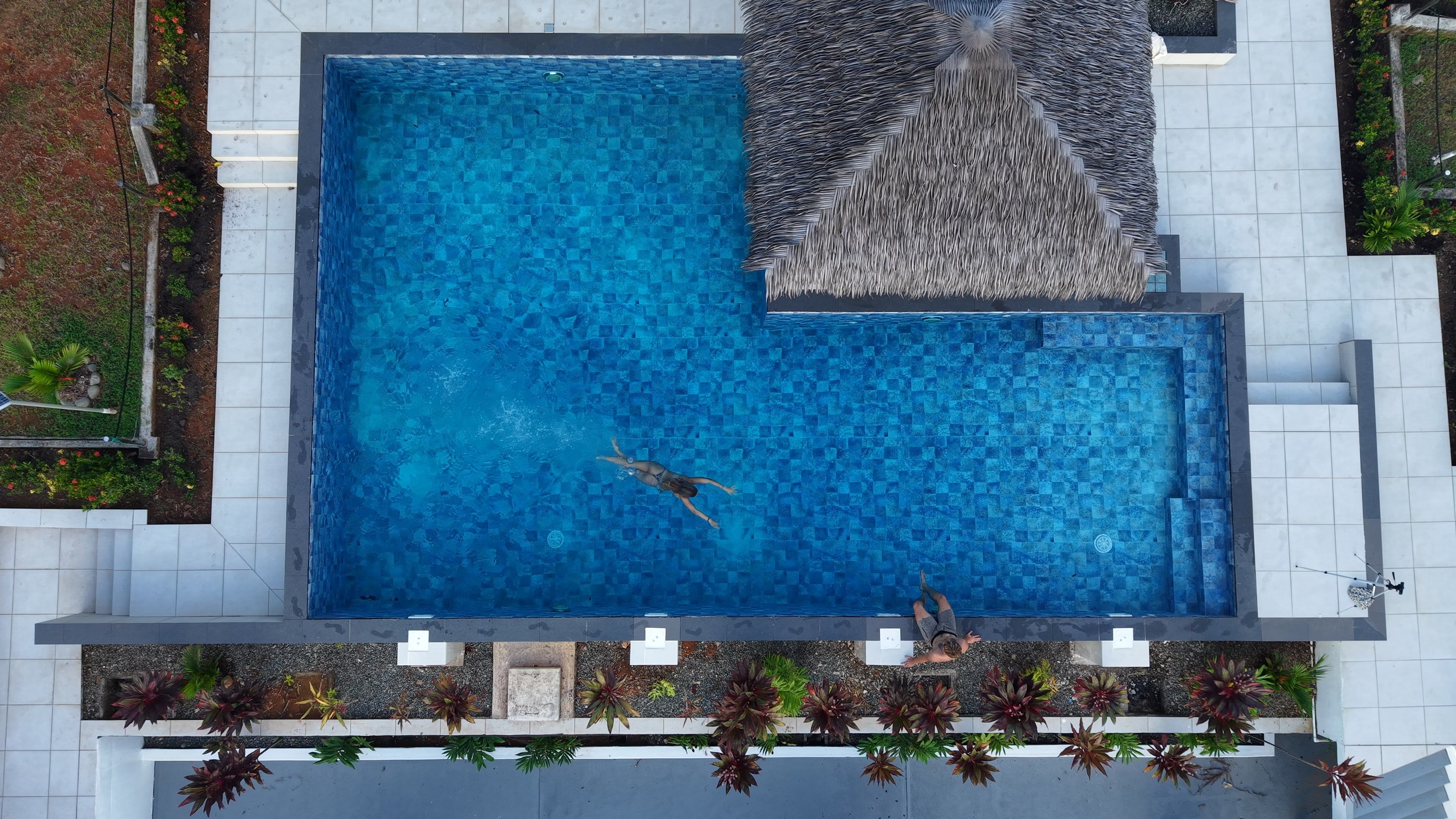 The pool from above, with one person swimming and another sitting on the edge